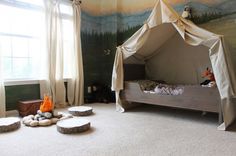 a bedroom with a canopy bed in the middle and pillows on the floor next to it