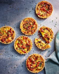 five small quiche pies sitting on top of a blue table cloth next to each other