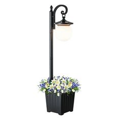 a black lamp post with flowers in it and a light on top of the pole