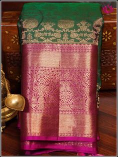 A Kanchipuram silk saree in a lush green shade, featuring intricate floral brocade designs is accentuated with a delicate pink border and pallu. This combination creates a captivating blend of colors and textures. The vibrant green tone symbolize freshness and vitality, while the floral brocade detailing adds an element of traditional charm and elegance. The gentle pink border infuses a soft and feminine touch, completing the graceful and natural aesthetic. Further, the floral and fauna motifs o Pink And Green Saree, Green And Pink Saree, Green Pattu Saree, Brocade Designs, Floral And Fauna, Lehenga Pink, Beaded Wedding Jewelry, Indian Wedding Gowns, Bridal Lehenga Designs