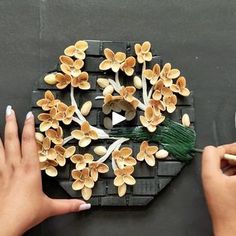 two hands are painting flowers on a piece of wood