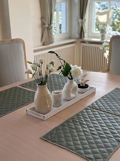 a wooden table topped with two vases filled with white flowers next to each other