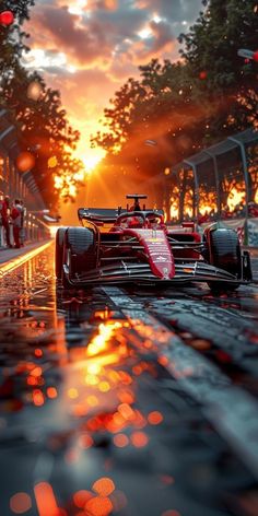 a red race car driving down a wet road at sunset with the sun in the background