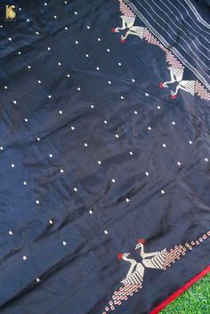 a blue cloth with two birds on it sitting in the grass next to a red and white blanket