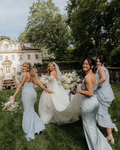 four bridesmaids are walking in the grass with their bouquets and dresses on