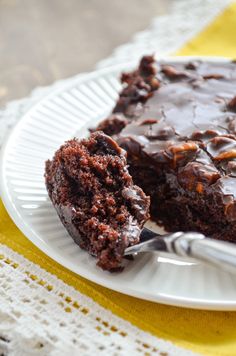 a piece of chocolate cake on a white plate with a fork in front of it