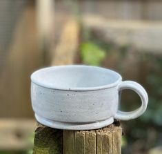 a white cup sitting on top of a wooden post