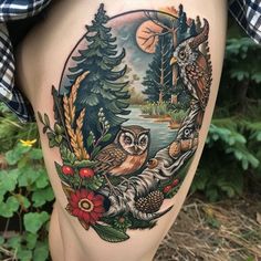 an owl tattoo on the side of a woman's thigh with trees and flowers around it