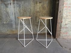 two stools sitting next to each other in front of a brick wall