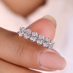 a woman's hand holding a five stone diamond ring