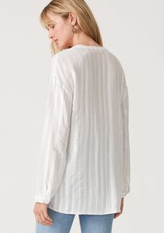 A timeless relaxed fit bohemian white shirt with embroidered detail. Embroidered Relaxed fit Long sleeve Single button closure at wrist High/low hemline Side vents V-neckline Button-front Bohemian white shirt An ultra-relaxed button front shirt designed in all-over tonal embroidery. Featuring long sleeves, a flattering v-neckline, and a subtle high-low hemline. Throw it on over your swimsuit for a quick cover-up, or tuck it into denim for a casual everyday feel. Model is 5'9, wearing a size S.St Spring Chic Blouse With Henley Neckline, White Blouse With Shirttail Hem For Daywear, Elegant Embroidered Relaxed Fit Blouse, Casual White Embroidered Top For Daywear, White Henley Neckline Top For Spring, Chic Henley Neckline Blouse For Spring, White Blouse With Shirttail Hem For Fall, Elegant White Embroidered Top For Daywear, Elegant Blouse With Floral Embroidery And Relaxed Fit