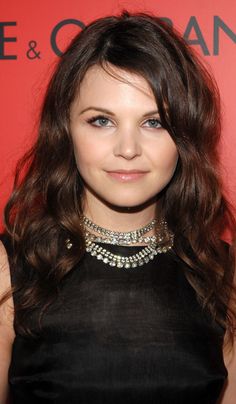 a woman with long hair wearing a black dress and choker is smiling at the camera