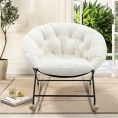 a white chair sitting on top of a rug next to a potted plant