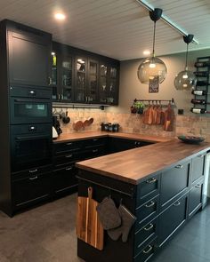 a kitchen with black cabinets and wooden counter tops