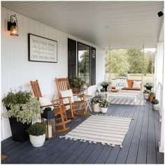 a porch with rocking chairs and potted plants on the front porch, along with an area rug