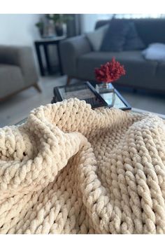 a white blanket sitting on top of a glass table next to a couch and coffee table