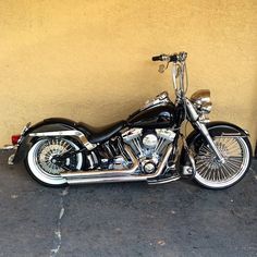 a black and silver motorcycle parked in front of a yellow wall with no one on it