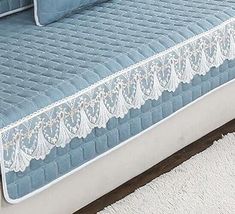 a bed with blue sheets and white lace on the bottom, along with two pillows