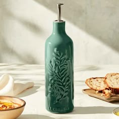 a green bottle sitting on top of a table next to some bread and other food