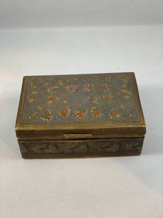 an ornately decorated metal box sitting on a white surface with no one around it