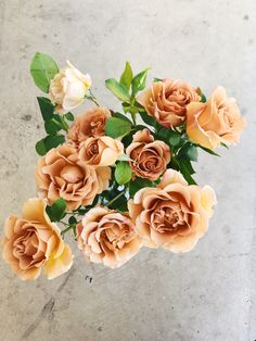 a vase filled with lots of flowers on top of a cement floor next to a wall