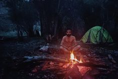 a man sitting in front of a campfire