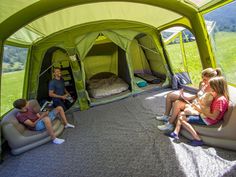 three people sitting on inflatable couches and talking to each other while camping