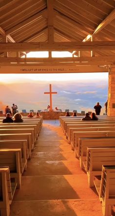 an empty church with benches and people sitting on the pews looking out at the water