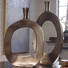 two metal vases sitting on top of a table