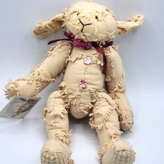 an old teddy bear that has been worn down and is sitting on the ground with a tag in it's ear