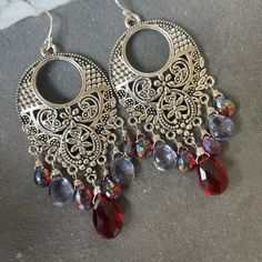 I have used two different kinds of mystic stones to show off these fun filigree silver alloy chandeliers. The blue stones are mystic quartz and the red ones are mystic rhodolite garnets. Please choose your choice of sterling silver earwires. The approximate length is 2.5". Your jewelry will arrive beautifully giftboxed. Red Dangle Jewelry With Gemstone Accents, Bohemian Gemstone Dangle Chandelier Earrings, Bohemian Gemstone Chandelier Dangle Earrings, Bohemian Gemstone Chandelier Earrings, Bohemian Sterling Silver Gemstone Chandelier Earrings, Bohemian Red Jewelry With Gemstone Accents, Bohemian Crystal Dangle Earrings With Gemstones, Bohemian Gemstone Chandelier Drop Earrings, Bohemian Silver Crystal Earrings With Gemstones