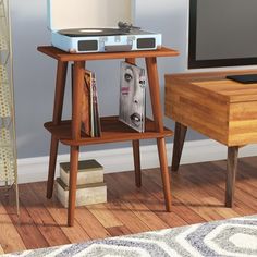 an old record player is sitting on a wooden stand next to a table with books and magazines