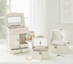 an assortment of white jewelry boxes with personalized items in them, on a table