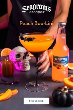 a person holding a drink in front of a table with halloween decorations