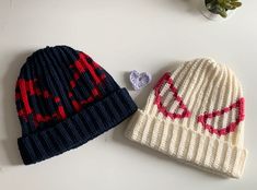 two knitted hats sitting next to each other on top of a white countertop