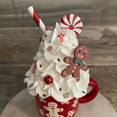 a cup filled with whipped cream and candy canes on top of a wooden table