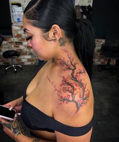 a woman with a tattoo on her back holding a cell phone