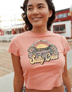 Salty Crew On Vacation Baby Tee. Large Graphic Screened On Front. Ribbed Crew Neckline. Short Sleeve. Woven Loop Label At Wearers Left Sleeve. Shrunken Fit. 100% Cotton. Machine Wash. Imported. Model Is Wearing A Size Small. Model Measurements:height: 5'8" Bust: 34"waist: 25"hips: 37.5" Fitted Tops With Front Print For Spring, Fitted Spring Tops With Front Print, Fitted Soft-washed Crew Neck Top, Fitted Soft-washed Graphic Tee, Cute Soft-washed Pink Top, Cute Pink Soft-washed Tops, Pink Soft-washed Graphic Tee, Spring Fitted Soft-washed Top, Spring Soft-washed Fitted Top