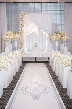 an aisle decorated with white flowers and greenery for a wedding ceremony at the ritz