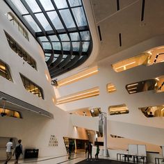 people are walking around in the lobby of a large building with high ceilings and glass windows