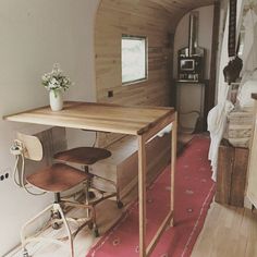 a small table and stools in a room with wood paneling on the walls