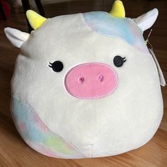 a stuffed unicorn pig sitting on top of a wooden floor