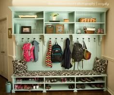 a bench with several coats and purses hanging on the wall next to it,