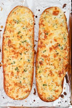 two cheesy breads sitting on top of foil in a baking pan with melted cheese