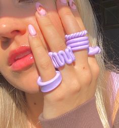 a woman with pink and purple nail polish holding her hands up to her face while wearing a ring