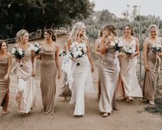 a group of bridesmaids walking down a dirt road