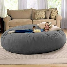 a woman laying on top of an orange bean bag chair in front of a couch