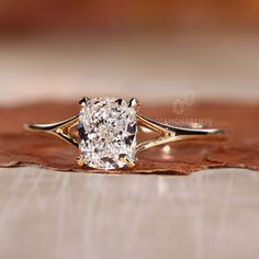 a close up of a diamond ring on top of a wooden surface with leaves in the background