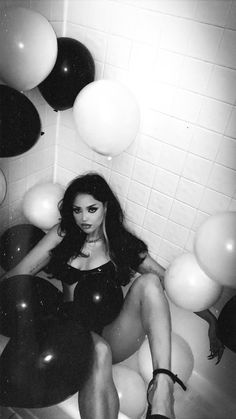 black and white photograph of a woman in a bath room with balloons on the wall