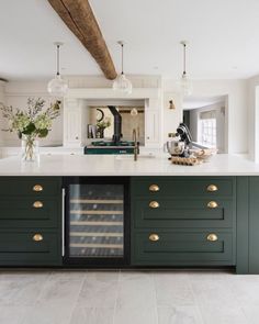 a large kitchen with green cabinets and white counter tops, an island in the middle